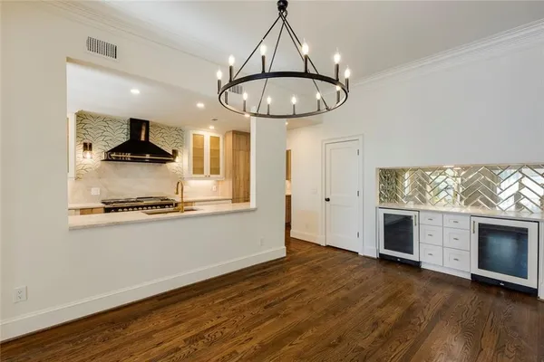 a kitchen with a chandelier stainless steel appliances and wooden floor