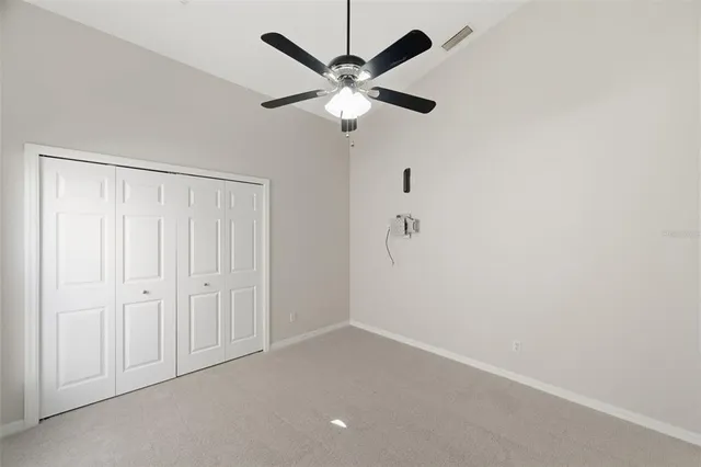 an empty room with closet and ceiling fan