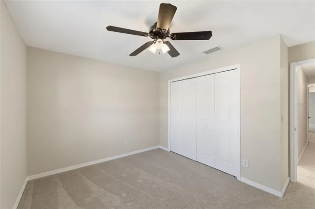 an empty room with ceiling fan and windows