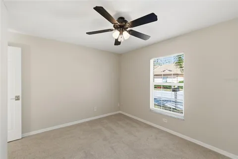 an empty room with ceiling fan and windows