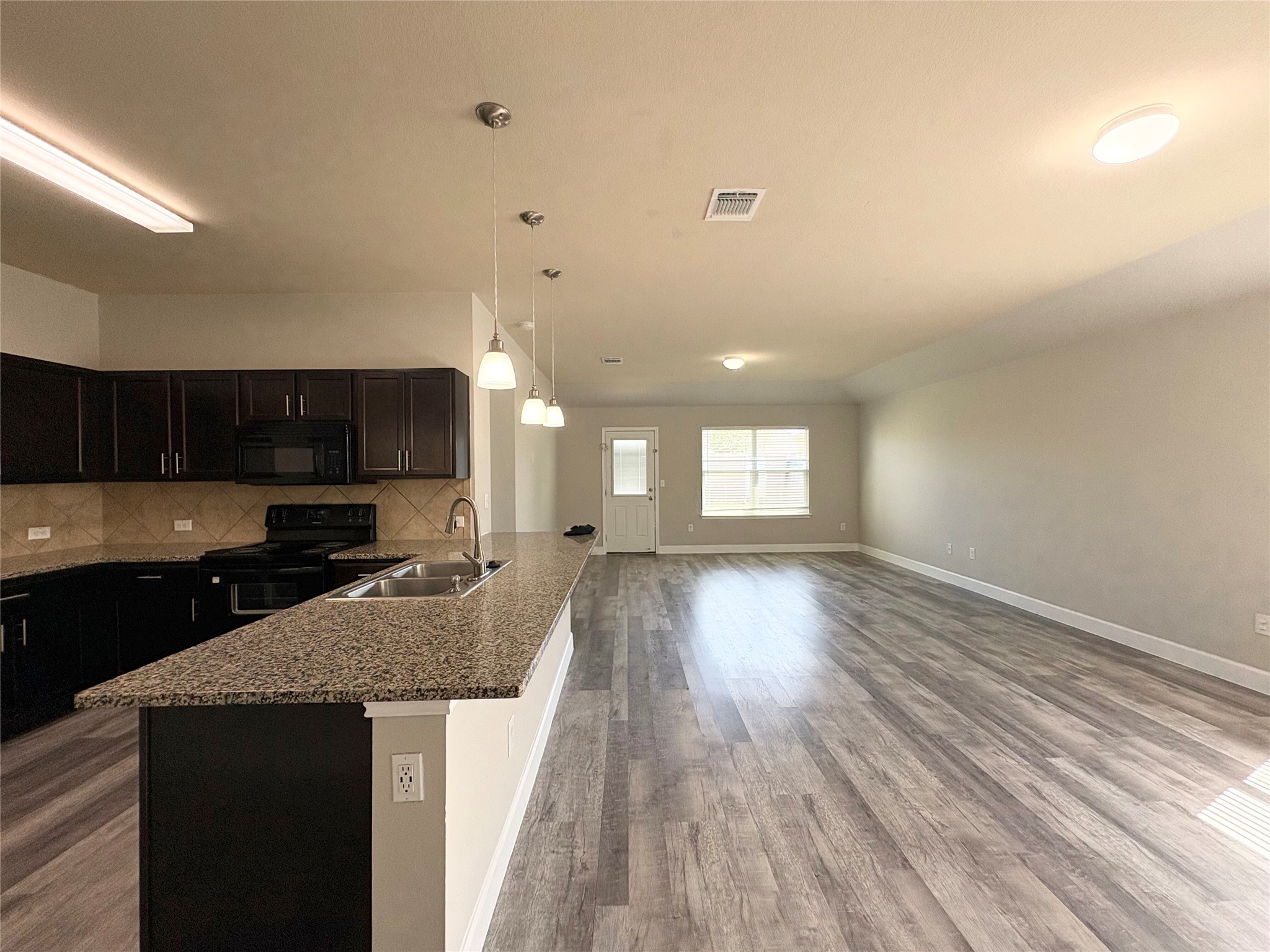 11708 Cambrian Road Manor, TX 78653 - Photo 13 of 31 An open-concept living space integrates a well-appointed kitchen with ample counter seating, perfect for entertaining.
