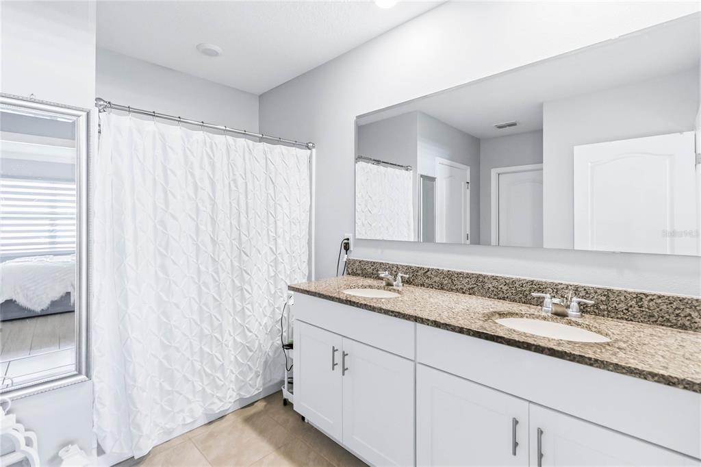 1759 Copinger Terrace Kissimmee, FL 34744 - Photo 16 of 29 a bathroom with a granite countertop sink and a mirror