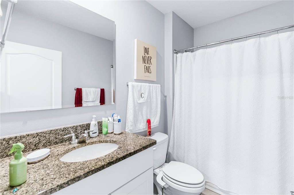 1759 Copinger Terrace Kissimmee, FL 34744 - Photo 22 of 29 a bathroom with a granite countertop sink mirror vanity and toilet