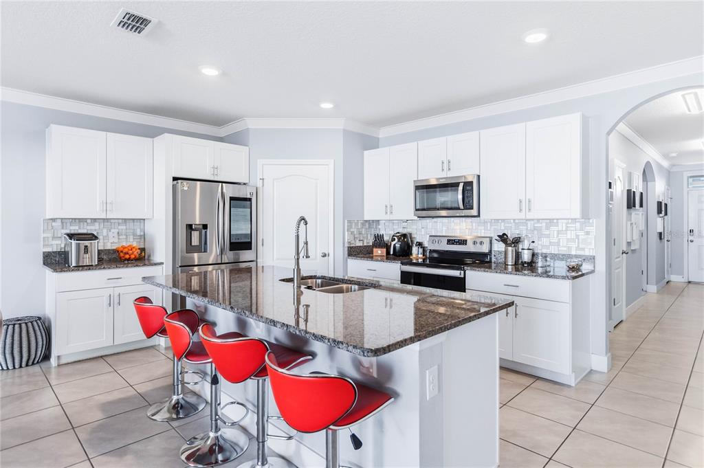 1759 Copinger Terrace Kissimmee, FL 34744 - Photo 9 of 29 a kitchen with stainless steel appliances granite countertop a refrigerator a stove a sink dishwasher and a dining table with chairs