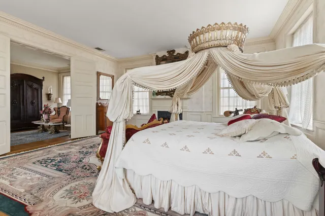 a view of a house next to a big yard and large trees