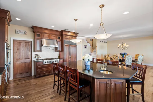 a kitchen with stainless steel appliances a dining table chairs stove and refrigerator