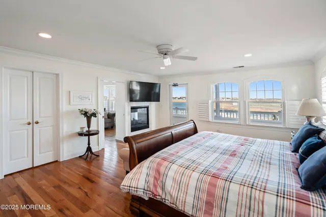 a bedroom with a bed wooden floor and a large window