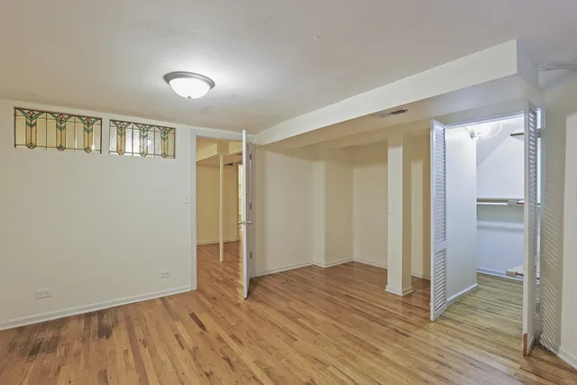 a view of an empty room with wooden floor and a bathroom