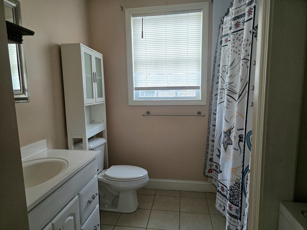 303 Eagle Street, Unit C Fall River, MA 02721 - Photo 22 of 32 a bathroom with a granite countertop toilet a sink a shower and a window
