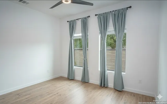 an empty room with wooden floor mirror and windows