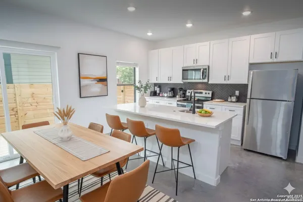 a kitchen with a refrigerator a stove a sink a dining table and chairs