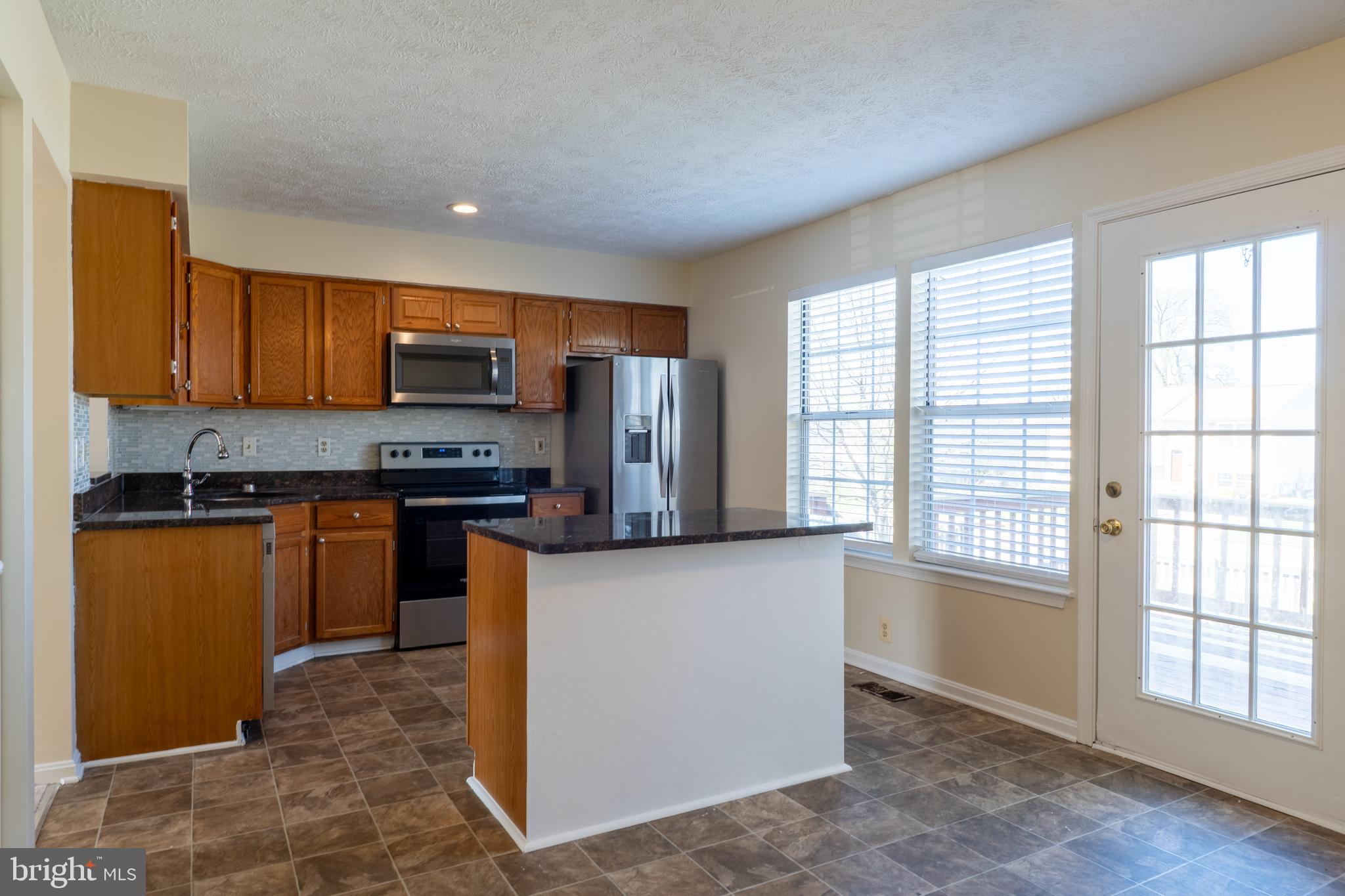 224 Oak Leaf Way Halethorpe, MD 21227 - Photo 7 of 32 a kitchen with stainless steel appliances granite countertop a stove a sink a refrigerator white cabinets and a window