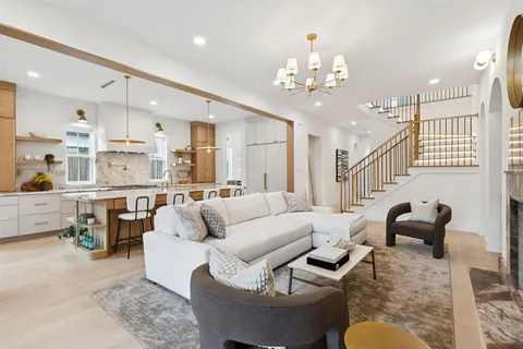 a living room with furniture kitchen view and a chandelier