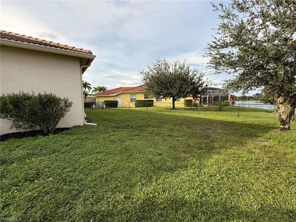 a white house that has a small yard and large trees