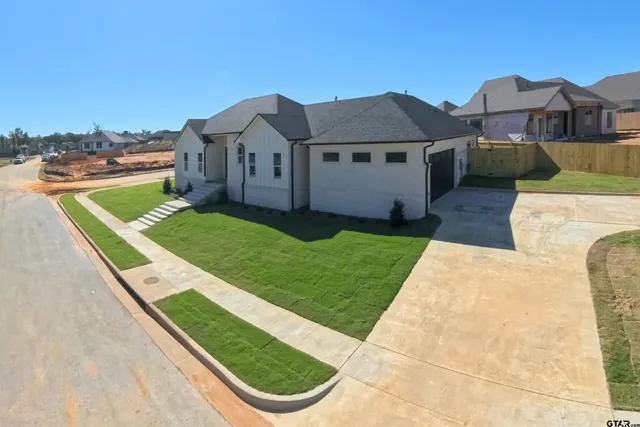 a view of a house with a big yard plants and large trees