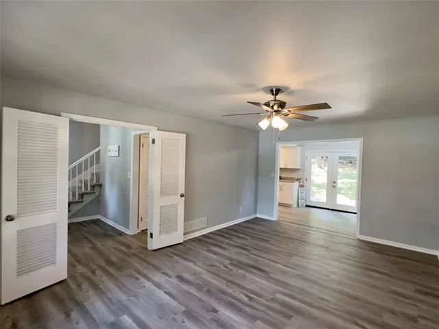 a view of an empty room with wooden floor and a ceiling fan