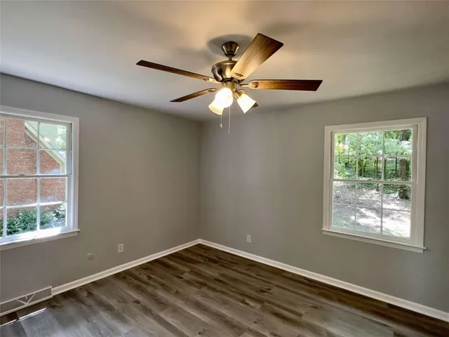 a view of an empty room with window and chandelier fan