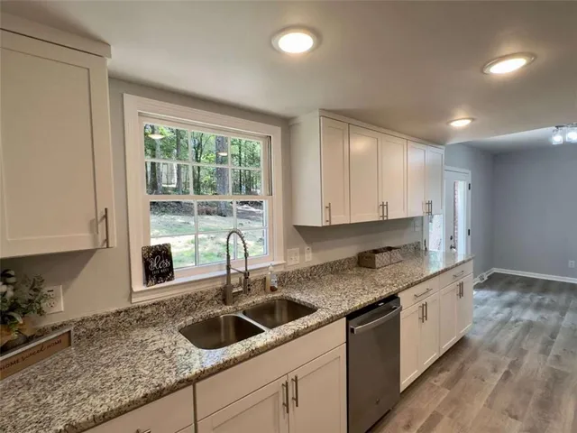 a kitchen with granite countertop a sink and a white wooden cabinets