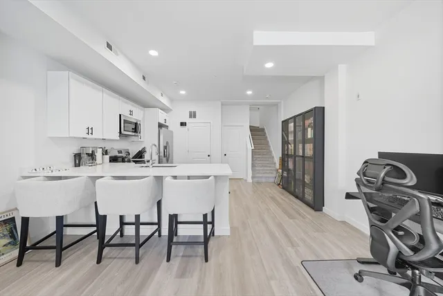 a kitchen with stainless steel appliances granite countertop a dining table chairs stove and white cabinets