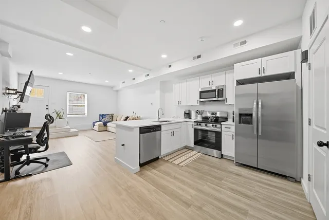 a large white kitchen with a refrigerator a stove a sink a dining table and chairs