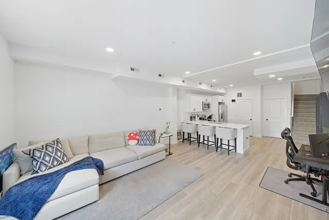 a living room with furniture and a dining table with kitchen view