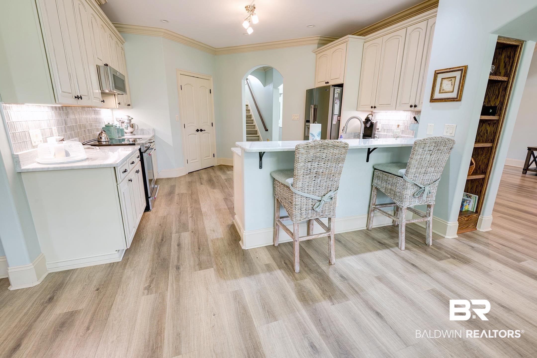 9357 Lakeview Drive Foley, AL 36535 - Photo 35 of 68 Modern kitchen featuring light wood-finish flooring, white cabinetry, a built-in microwave, and a breakfast bar with stone-look countertop