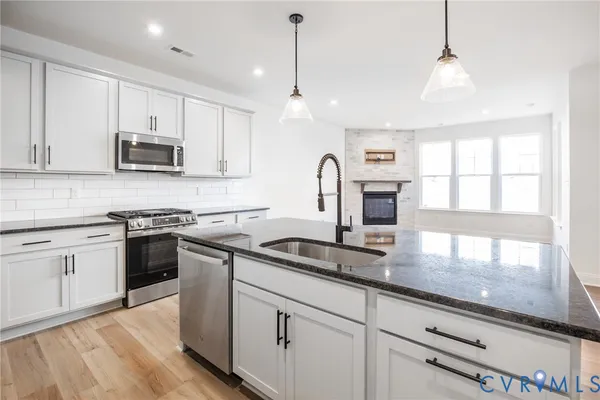 a kitchen with granite countertop a stove a sink and a microwave