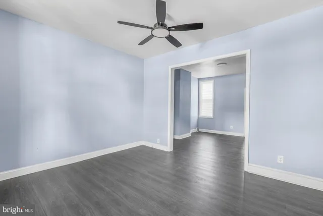 a view of empty room with wooden floor and ceiling fan