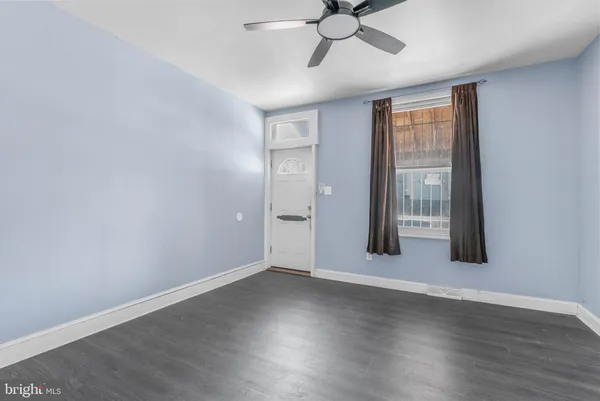 an empty room with wooden floor fan and windows