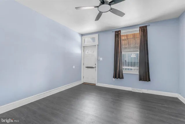 an empty room with wooden floor fan and windows