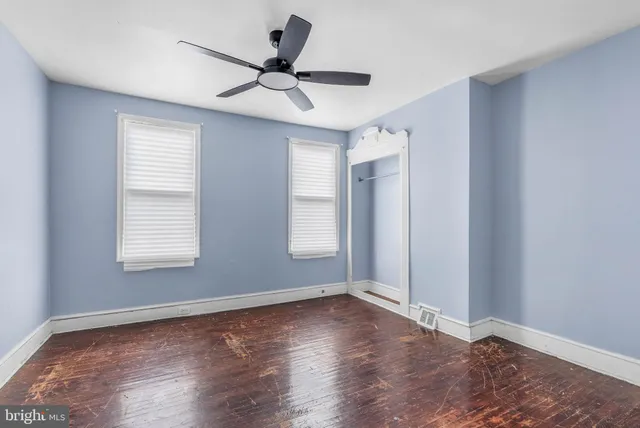 a view of empty room with wooden floor and fan