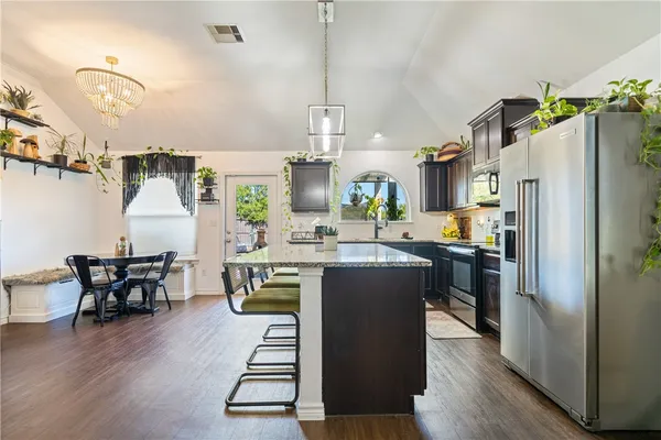 a kitchen with stainless steel appliances granite countertop a refrigerator a stove a sink dishwasher and white cabinets with wooden floor