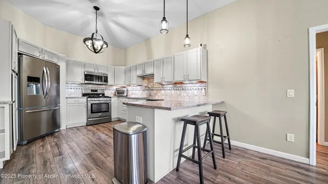 a kitchen with stainless steel appliances granite countertop a table chairs refrigerator and microwave