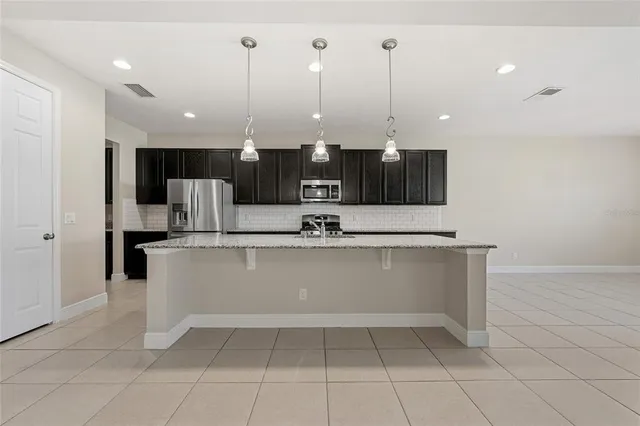 a view of kitchen with stainless steel appliances granite countertop a sink a stove and a refrigerator