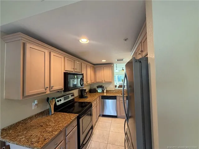a kitchen with granite countertop a stove top oven microwave and refrigerator