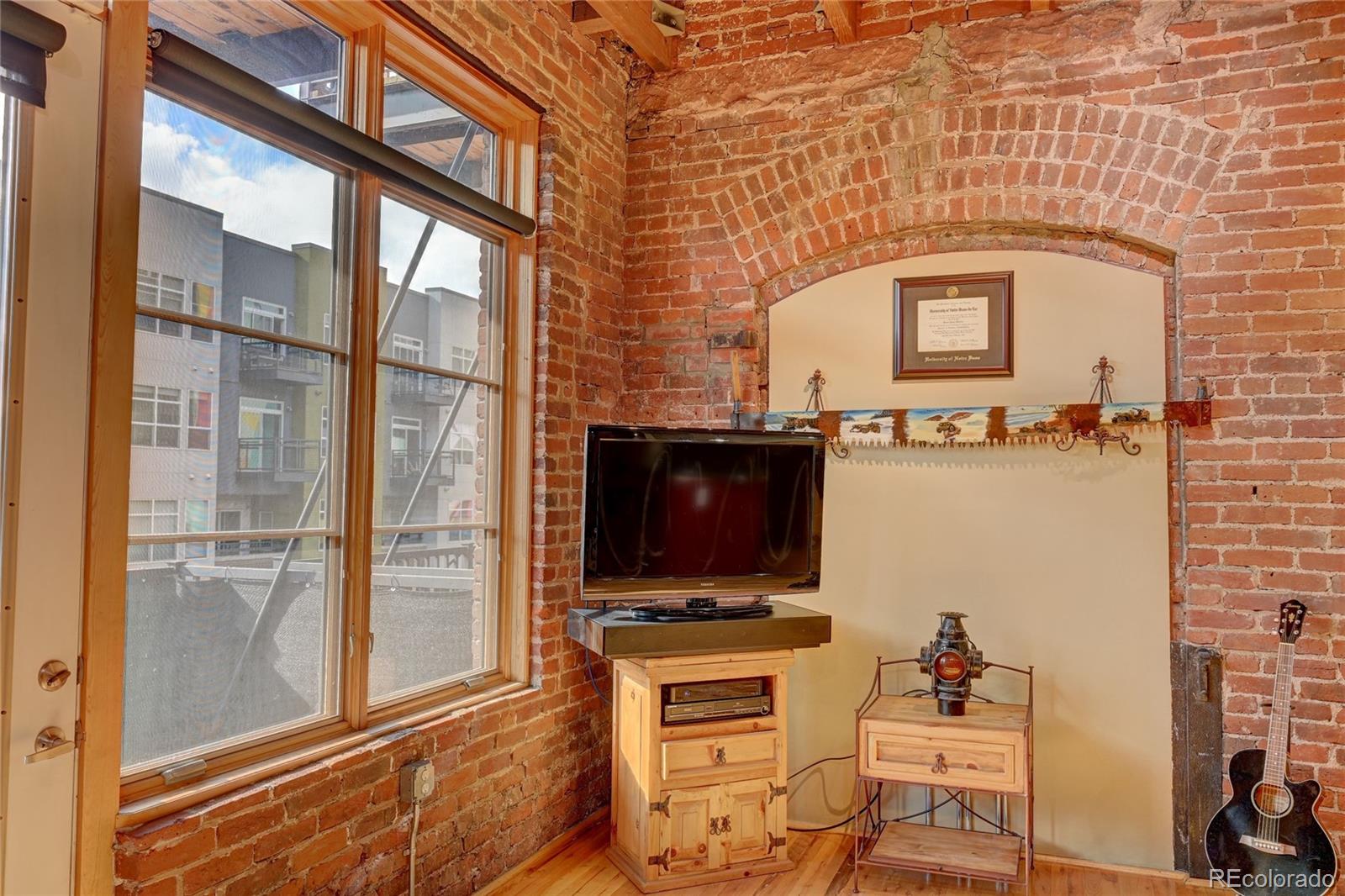 2960 Inca Street, Unit 313 Denver, CO 80202 - Photo 10 of 27 a living room with furniture a flat screen tv and a floor to ceiling window