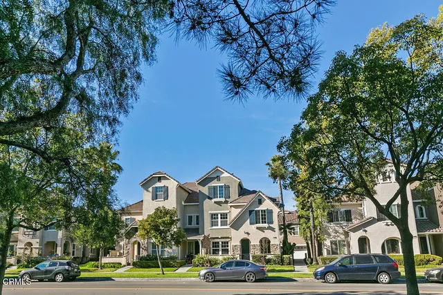 a front view of a building with trees and umbrellas