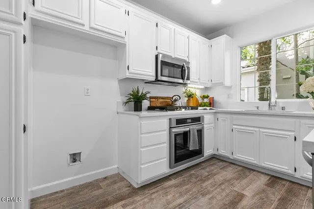 a kitchen with white cabinets and sink