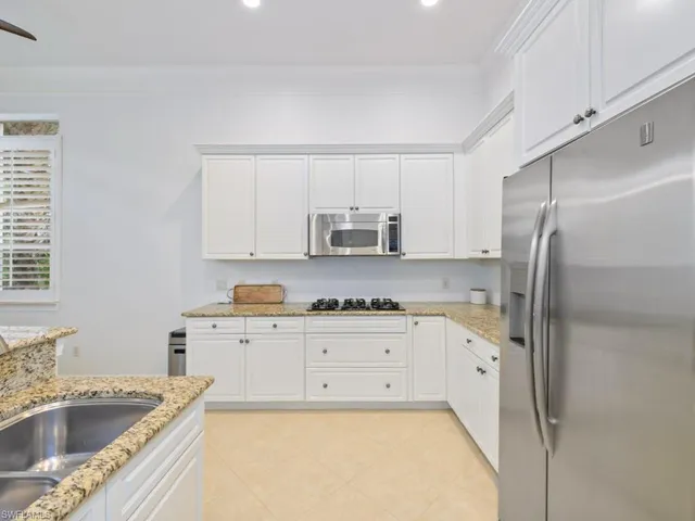 a kitchen with granite countertop a sink a stove and refrigerator