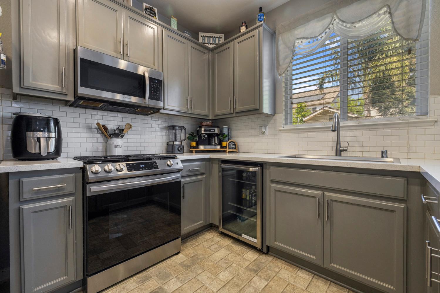 3145 Sweet Pea Avenue Merced, CA 95341 - Photo 14 of 25 a kitchen with stainless steel appliances granite countertop a sink dishwasher a stove and a microwave oven with cabinets
