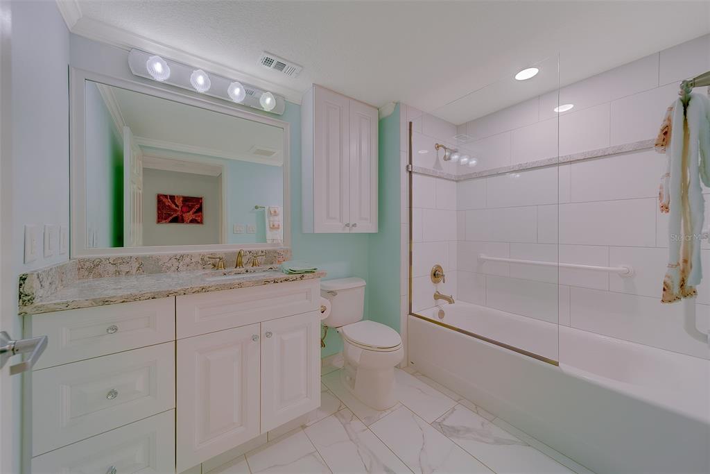 16450 Gulf Boulevard, Unit 565 North Redington Beach, FL 33708 - Photo 46 of 54 a bathroom with a granite countertop sink a toilet a mirror and shower