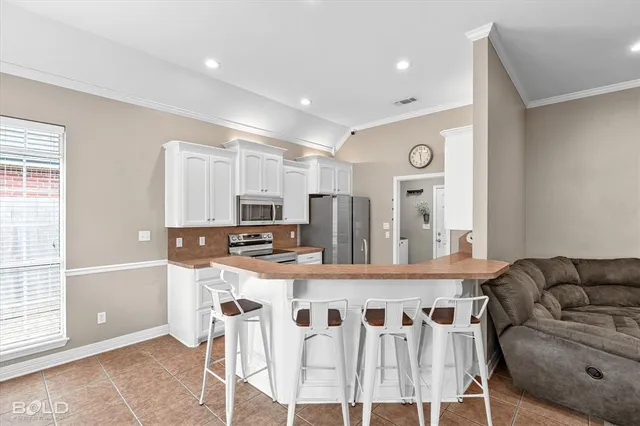 a kitchen with stainless steel appliances kitchen island granite countertop a refrigerator a stove a microwave oven with a dining table and chairs