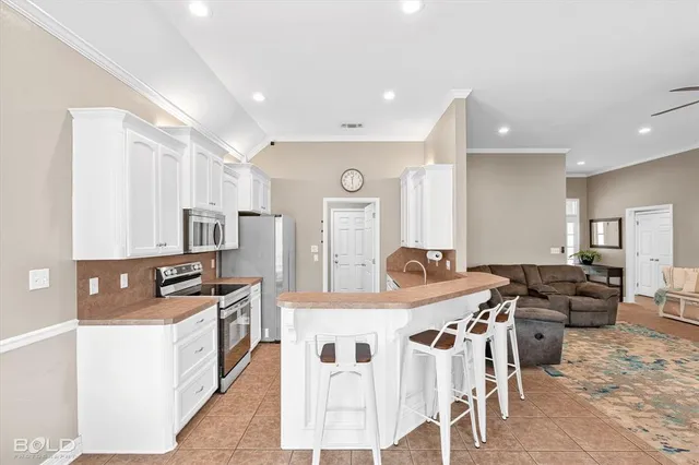 a kitchen with stainless steel appliances kitchen island granite countertop a stove a sink a dining table and chairs