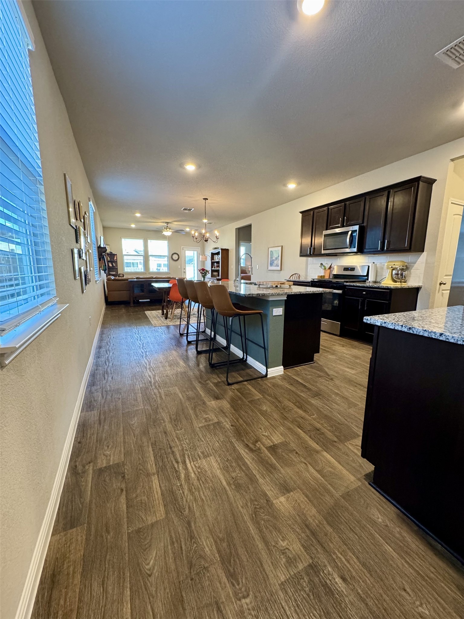 107 Hamilton Pool Lane Bastrop, TX 78602 - Photo 6 of 22 Kitchen featuring a center island with sink, light stone countertops, stainless steel appliances, and a chandelier.