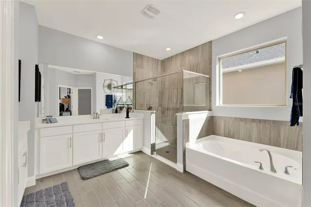 a bathroom with a white bath tub a mirror and a sink