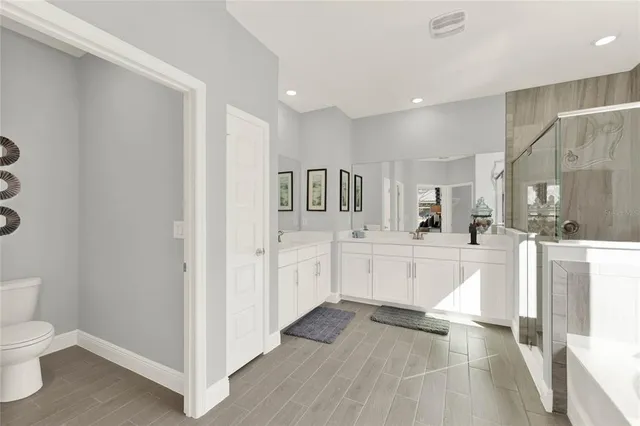 a large white kitchen with lots of counter space and wooden floor