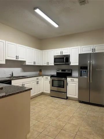a kitchen with granite countertop a refrigerator and a stove top oven