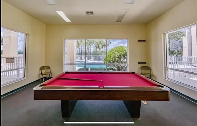 a room with pool table and windows
