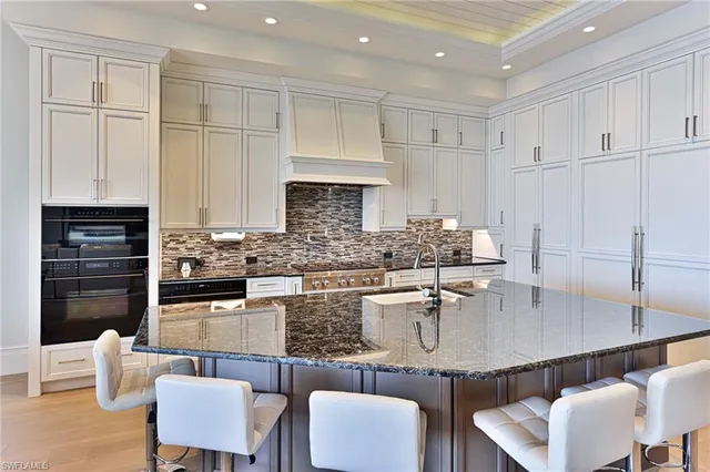 a kitchen with kitchen island granite countertop a table chairs sink and cabinets