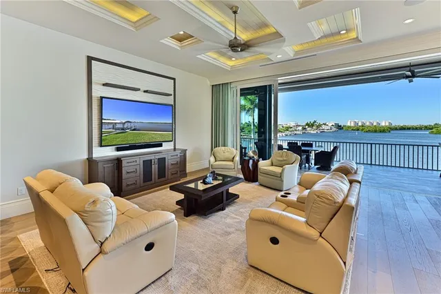 a living room with furniture a flat screen tv and a floor to ceiling window